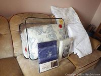 Photo of new packaged table linens and bedding including reversible comforters, duvet, and tablecloth, all displayed on a couch.