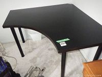 Overall view of black corner computer table showing L-shape, cutout corner, metal legs, and black laminated MDF surface.