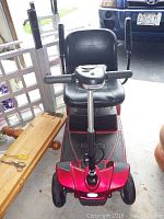 Front view of red mobility scooter showing tiller, seat and front wheels