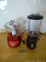Both kitchen choppers side by side on wooden surface against white wall, with cords visible