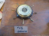 Image showing front of Ingraham ships wheel barometer on wooden surface with price tag.
