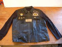 Full front view of ladies Harley leather and knit top laid flat on table showing front zipper, leather front, knit sleeves, and patches.