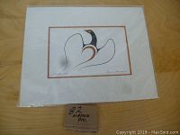 Photo of the native art print matted, showing the black, white, and orange stylized bird image titled "Lost From Flock".