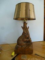 Front view of carved wooden lamp showing bear figure and wooden tone patchwork lampshade.