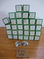 Stack of 35 Dymo tape boxes containing blue label tapes, with two plastic Dymo tape dispensers in front