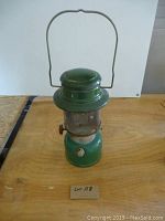 Full view of the green Coleman Model 335 lantern showing metal body, glass globe, control knob, and handle.