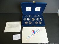 Full view of blue velvet presentation case with coin set and cards, showing all coins in capsules and original accompanying papers.