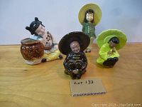 Four oriental-themed ceramic planters and figurines displayed on wood surface with lot number card