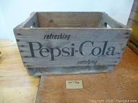 Side view of wooden crate with "refreshing Pepsi-Cola satisfying" stamped text.