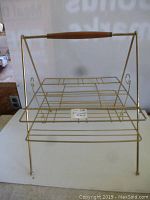Full front view showing the mid century metal wire rack with wooden handle, highlighting the overall shape and design.