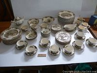 Full set arranged on table showing plates, bowls, cups, saucers, teapot, etc.