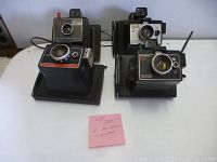 Front view of all four Polaroid cameras on display, showing the ZIP (top left), Square Shooter II (top right), Colorpack IV (bottom left), and Colorpack 82 (bottom right) on a flat white surface.