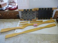 Overview of all wooden canoe parts including yoke, yak seats and various components on white surface