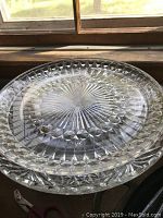 Two stacked cut glass serving dishes showing diamond and starburst pattern on top dish