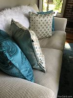 Close-up of the love-seat cushions and decorative pillows in teal and patterned colors.