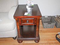 Front view showing wooden side table with drawer, lower open shelf, minor scratches on surface
