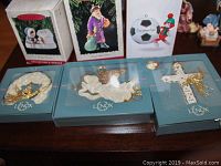 Photo shows three Lenox ornaments in original boxes: a wreath, an angel playing trumpet, and a cross with a gold angel figure; also three Hallmark boxed ornaments including Santa Claus, snowman, and a soccer ball with elf design.