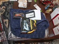 Full view of all lot items including Cosi Concepts men's sleepwear set, EWatch Factory wristwatch, and Meguiar's car wax box on top of men's collared shirt.