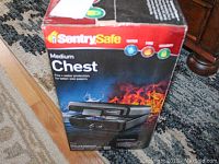 Photo of the sealed box showing Sentry Safe Medium Chest, highlighting fire and water protection branding.