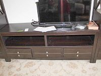 Front view of media cabinet middle piece showing three drawers and a TV on top.