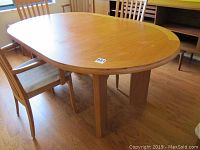 Full view of the teak dining table with four matching chairs around it, showing top surface and structure.