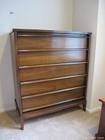 Front view of chest showing five drawers and medium brown finish.