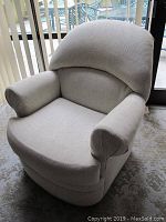 Front view of beige upholstered swivel chair showing cushion, arms, and fabric texture.