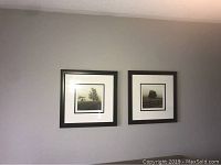 Two framed artworks hanging on a wall, featuring images of trees near fences.