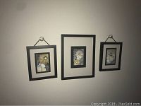 Three framed flower pictures, two with hanging ribbons and one plain black frame