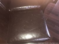 Close-up photo of the top surface of the ottoman showing scratches and wear on the faux leather material.