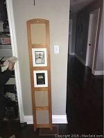 Vertical wooden picture frame hanging on a wall, showing five photo slots, two with black and white photos.