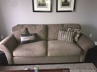 Front view of green micro suede couch with three decorative pillows showing wear and marks on cushions and arms.