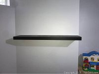 Front view of one floating espresso Ikea shelf mounted on a white wall, showing depth and finish