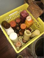 Yellow crate with assorted used candles of various sizes and colors including pillar and jar styles