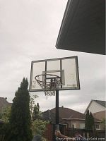Outdoor basketball hoop with metal rim and net attached to a clear backboard with Spalding branding. Hoop mounted on a black pole.