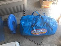 Photo showing the blue blower and Kidpwer Bounce 'Round storage bag containing the inflatable bouncer.