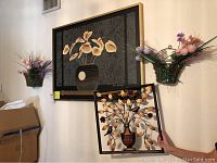 View of the large framed wall picture, two hanging wire baskets with artificial floral decor on either side, and the metal wall decor positioned in front of the picture leaning against the wall.