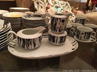 Overview of Cuisena Eclipse black and white porcelain dinnerware including tea cups, small plates, and serving dishes