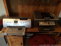 Two printers on a wooden desk, HP Photosmart 7960 on left and Lexmark X7350 on right.