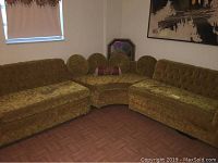 Photo of the three-piece vintage sectional upholstery sofa arranged in corner with tufted back cushions, showing mustard yellow velour fabric, rolling legs, and two round pillows with one bolster pillow.