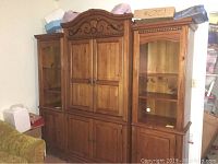 Photo of the three-piece wooden wall unit including left, middle, and right sections with TV armoire in room