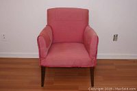 Front view of the vintage pink side chair showing pink fabric upholstery and dark wooden legs, highlighting armrests and general shape.