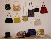 All 18 vintage evening purses and bags including beaded, metal mesh, fabric and sequin designs shown hanging and on table