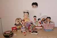 Front view of entire Betty Boop collectibles lot showing all 14 items including figurines, clock, music box, and banks