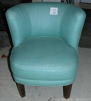 Front view of mid century barrel back side chair with aqua green fabric upholstery and wooden legs.
