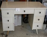 Front view of the mid century modern desk showing 7 drawers and original black hardware pulls. White finish with some wear visible. One left-side leg shown mostly intact.