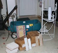 Tiles and garden items including plant stands, metal buckets and a plastic pull cart on a floor indoors.