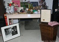 Overall view of vintage and contemporary home decor items on and under a table including framed pictures, glassware, crystal beaded fruit, candle holders, and small decorative items.
