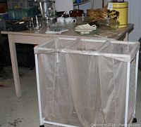 Three-bag mesh laundry cart with white metal frame and caster wheels in garage setting