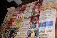 Image displaying assorted vintage historic newspapers and magazines spread out on a surface, including Time, The New York Times, George, and more